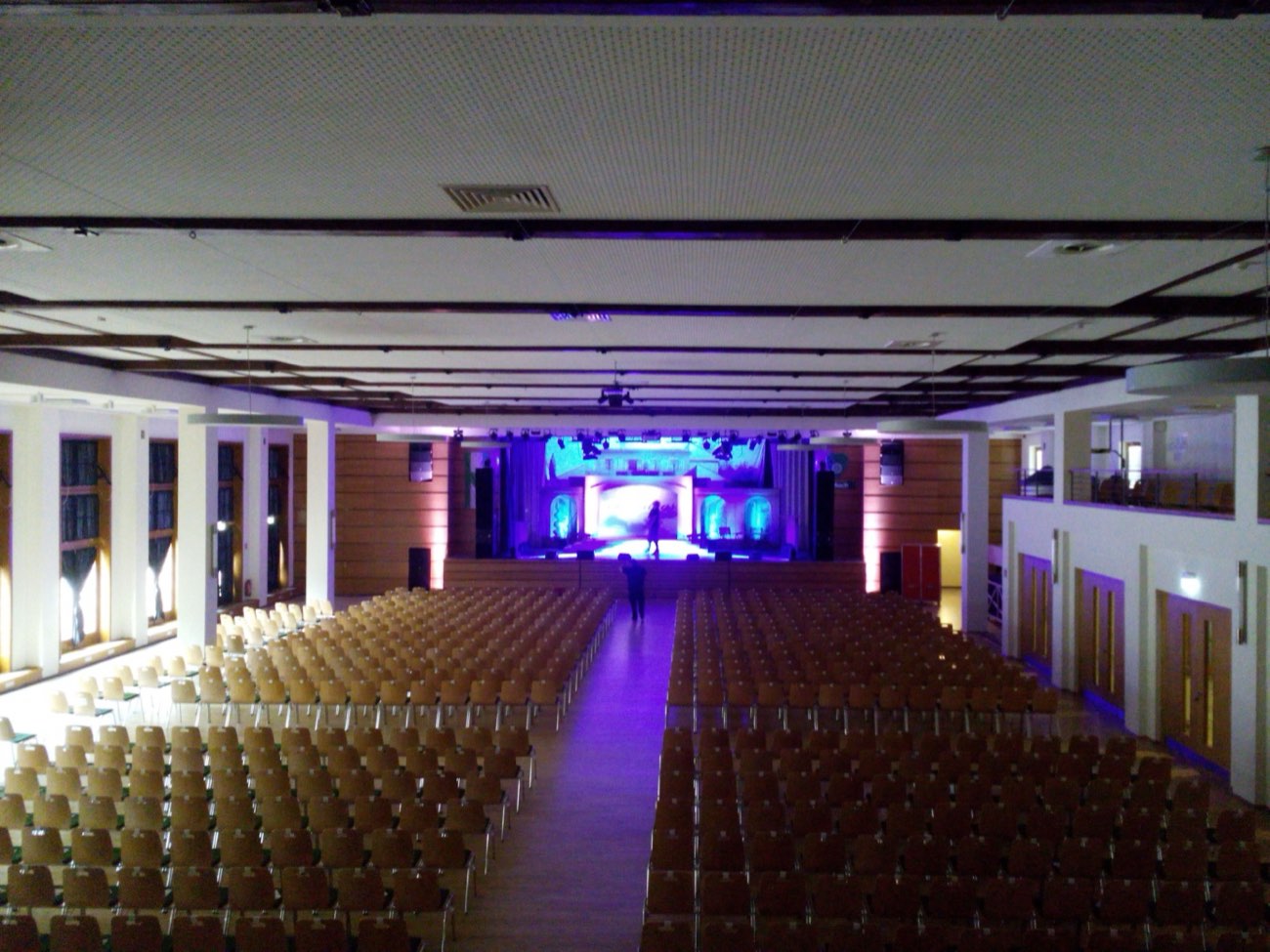 Der Saal in Reihen bestuhlt, Blick zur beleuchteten Bühne